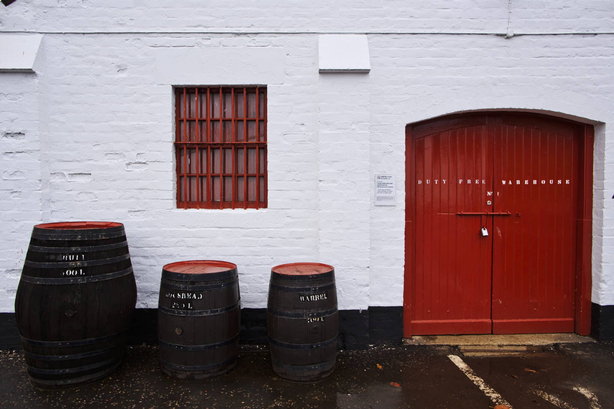 Whisky barrels stand outside a warehouse.